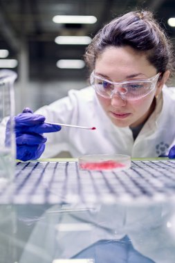 Female laboratory assistant with petri dish in hands