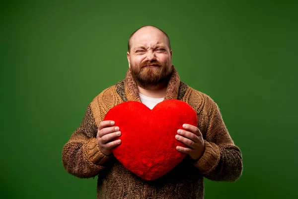 Ráncos férfi kezében játék szív, miközben áll az üres zöld háttér — Stock Fotó
