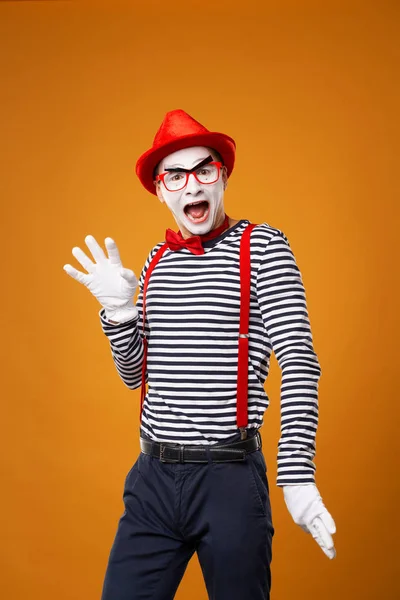 Hombre mimo sonriente mirando a la cámara en chaleco y sombrero rojo Aislado sobre fondo naranja — Foto de Stock