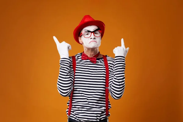 Mime em chapéu vermelho e colete mostrando polegar no fundo laranja — Fotografia de Stock