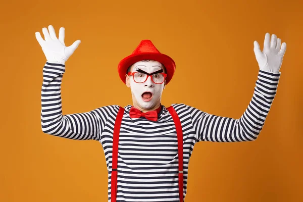 Surprised mime man in red hat and in vest with hands up on orange background — 图库照片