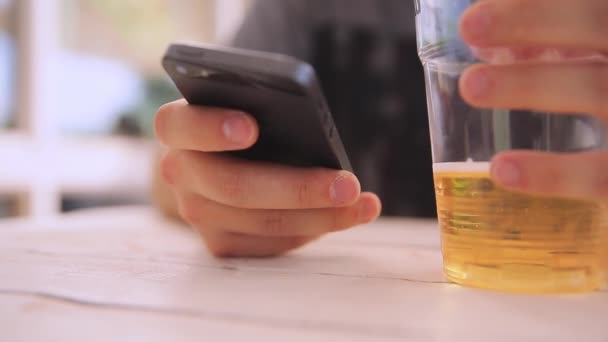 Мужчина болтает со смартфоном, пьет пиво . — стоковое видео