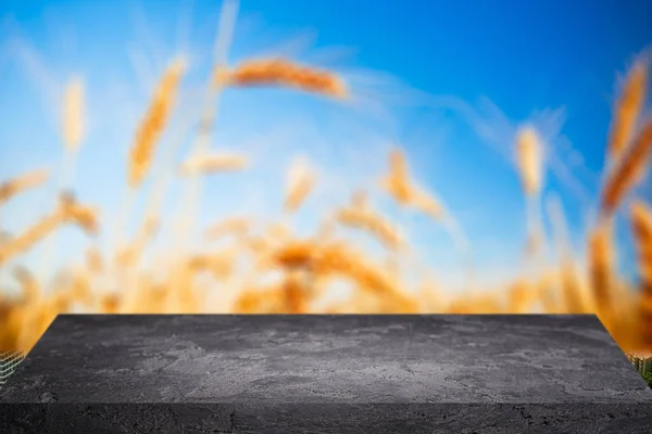 Superficie in pietra nera trasparente su sfondo sfocato di grano, cielo blu, primo piano . — Foto Stock