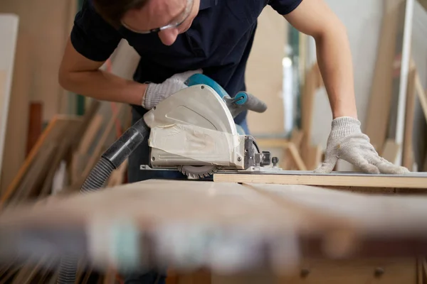 Homme en lunettes de sécurité et gants blancs travaille sur puzzle en atelier — Photo