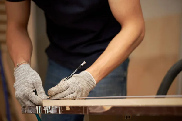 Erkek marangoz atölyesinde dar bir tahta tutuyor. — Stok fotoğraf