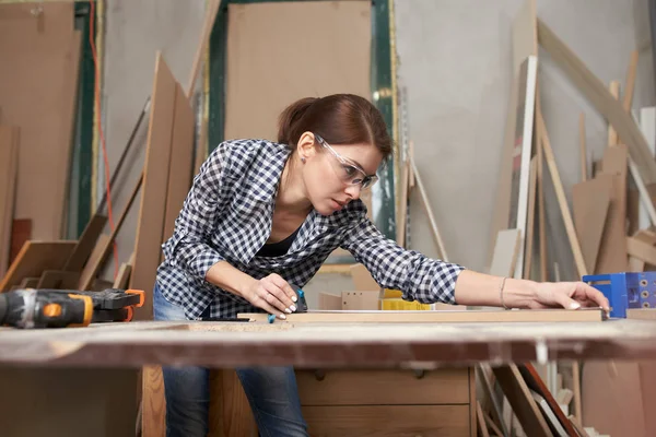 Vrouw houtbewerker met houten plank achter werkbank — Stockfoto