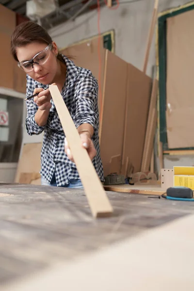 Дівчина тесля в окулярах з дерев'яними дозами і олівцем в руках — стокове фото