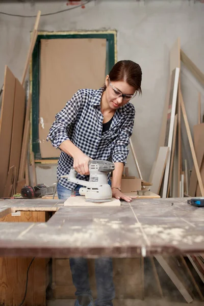 Jonge vrouw timmerman in bril werken met fretsaw. — Stockfoto