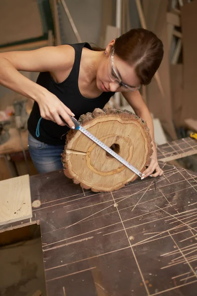 Brunette timmerman met tape maatregel en zaag gesneden boom in haar handen — Stockfoto