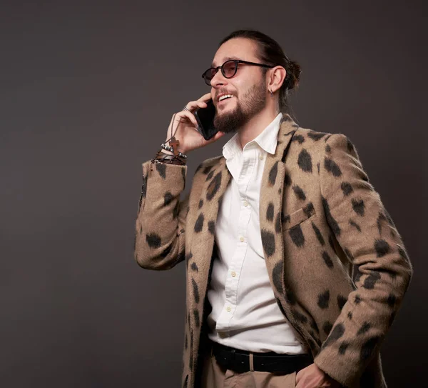 Mann mit Sonnenbrille in Jacke telefoniert auf braunem Hintergrund — Stockfoto