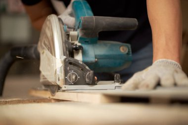 Hands of carpenter man sawing wooden boards with jigsaw