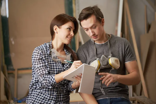 Man en vrouw schrijnwerkers met notebook in hun handen — Stockfoto