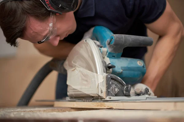 Carpenter in white gloves works on jigsaw in workshop — Stock Photo, Image