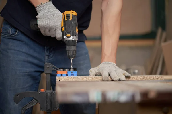 Mannelijke timmerman met boor en plank in werkplaats — Stockfoto