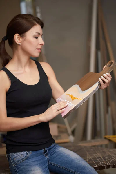 Brunette woman with picture on cutting board sits on table — Stockfoto