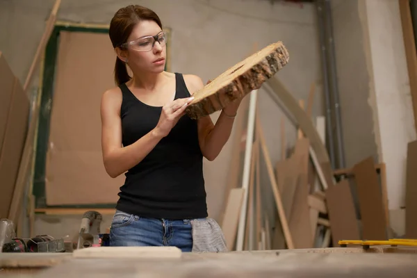 Brunette carpenter with saw cut tree in hands — Stockfoto