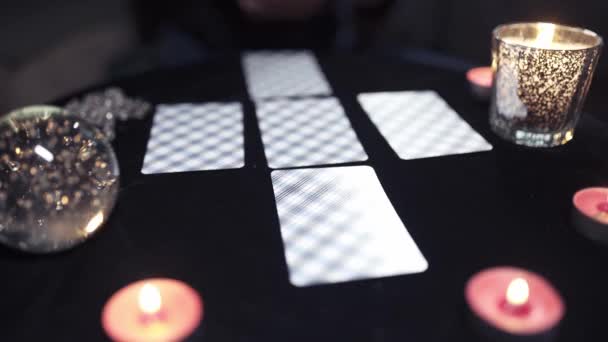 Крупным планом карты выложены на черном столе со свечами — стоковое видео