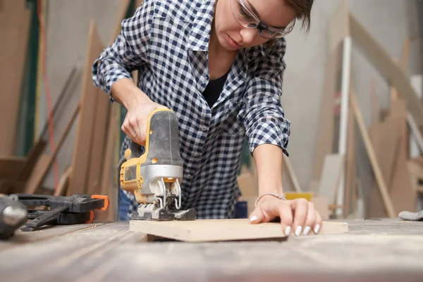 Brunette nainen puuseppä työskentelee fretsaw — kuvapankkivalokuva