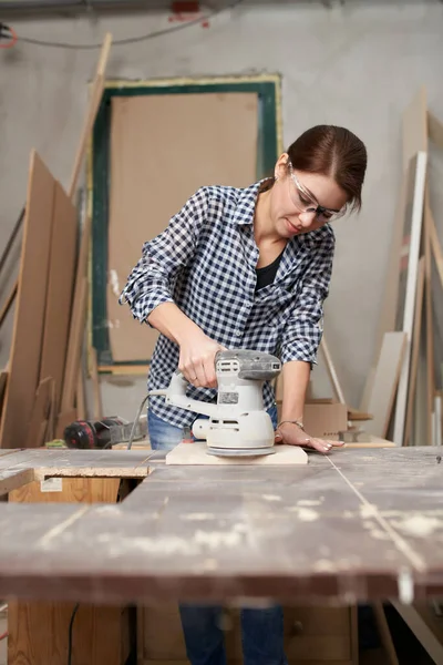 Vrouw timmerman in bril werken met fretsaw. — Stockfoto