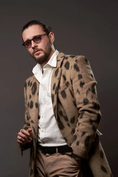 Seriöser Mann mit Sonnenbrille in Jacke vor braunem Hintergrund — Stockfoto