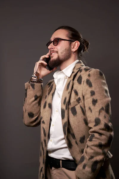 Hombre en gafas de sol en chaqueta hablando por teléfono sobre fondo marrón — Foto de Stock