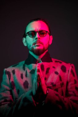 Ceketli, sakallı, gözlüklü bir erkek.