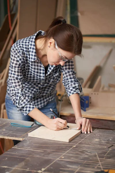 Close up carpenter girl in glasses with tape measure and blackboard — ストック写真