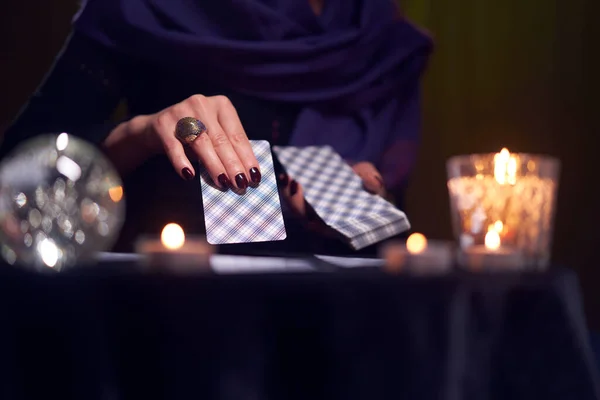 Close-up of woman fortunetellers hands with cards at table with candles, magic ball in dark room — Stock Photo, Image