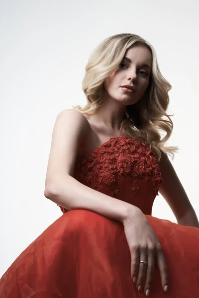 Young woman in red dress looking at camera in studio — Stock Photo, Image