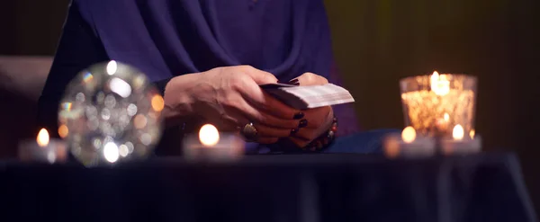 Mujer adivina adivina en tarjetas sentadas a la mesa con velas encendidas, bola mágica — Foto de Stock