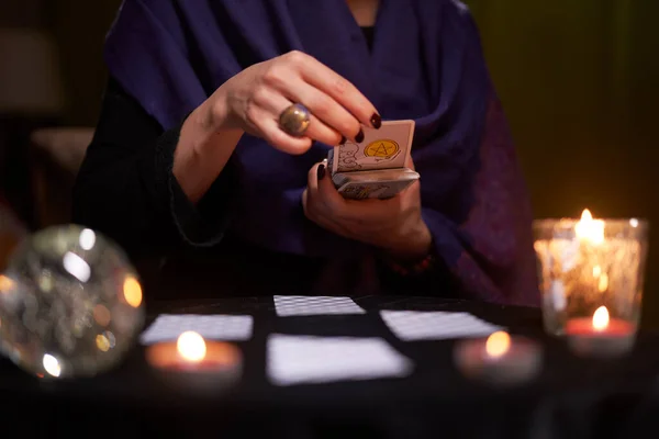 12.02.20. Moscow, Russia. Fortuneteller divines on cards at table with candles in dark room — Stock Photo, Image