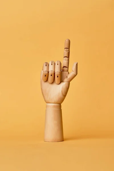 Wooden hand with finger raised up on orange background — Stock Photo, Image