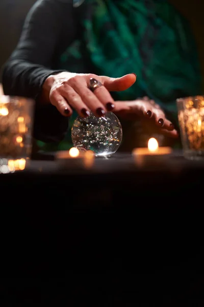 Fortuneteller female divining on magic ball at table with burning candles — Stock Photo, Image