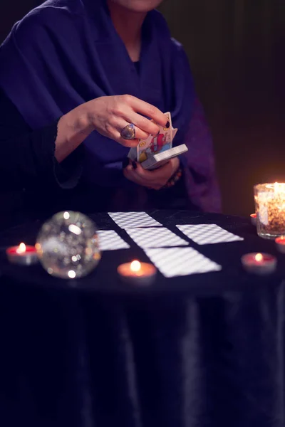 Fortune teller in blue dress divines on cards sitting at table with candles — Stock Photo, Image