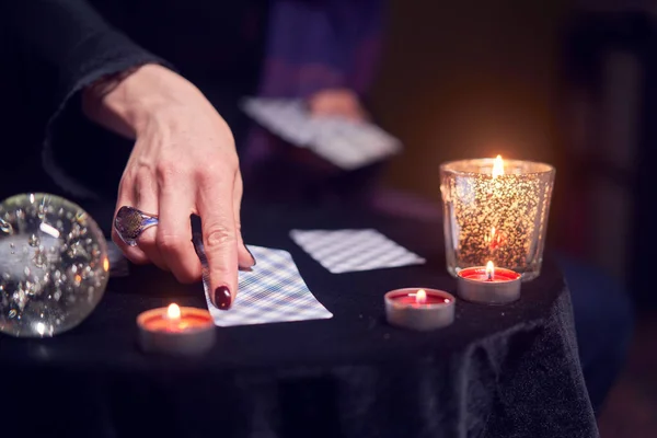 Primer plano de las adivinas manos con tarjetas de adivinación en la mesa con velas — Foto de Stock