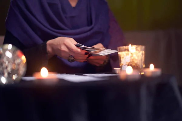 Närbild av spåkvinna spådom på kort sitter vid bordet med brinnande ljus, magiska bollen — Stockfoto