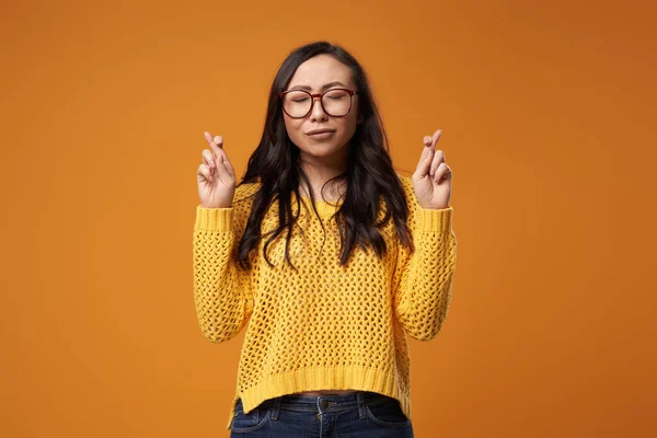 Mujer en gafas y en jersey con dedos cruzados en estudio — Foto de Stock