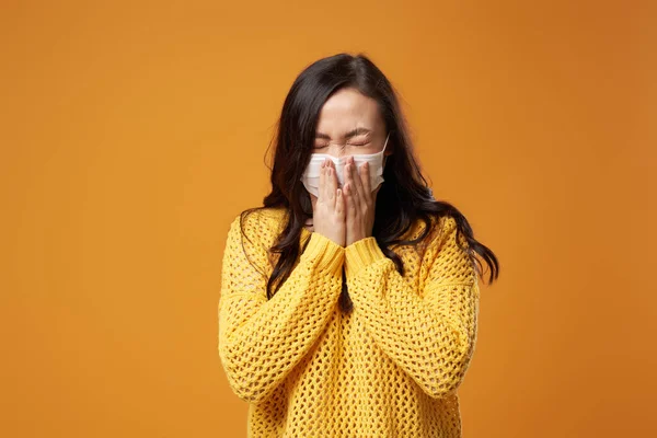 Masked woman sneezes while standing in studio — Stock Photo, Image