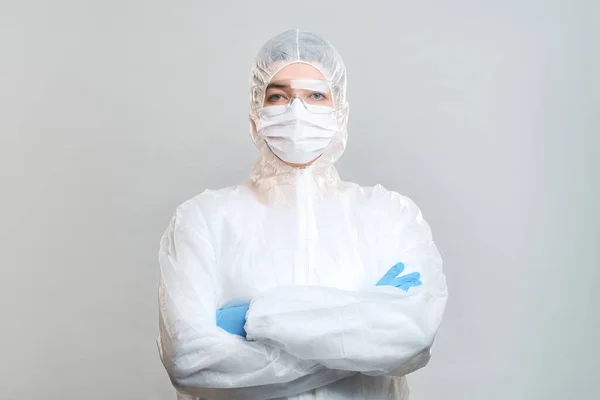 Uomo in tuta protettiva, maschera medica, occhiali con le braccia incrociate. Isolato in studio — Foto Stock