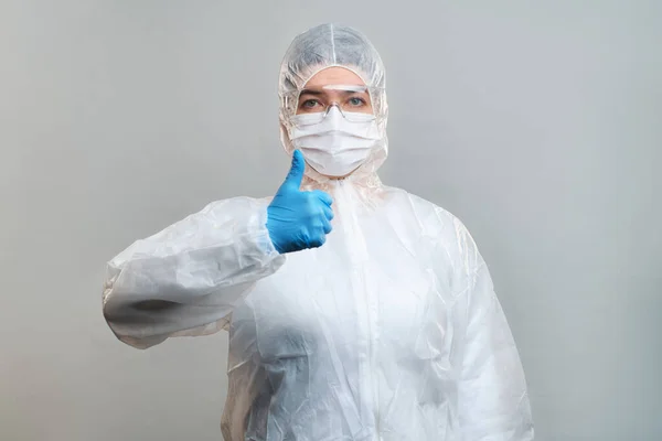 Человек в защитном костюме, медицинская маска, защитные очки с поднятым пальцем изолированы в студии — стоковое фото