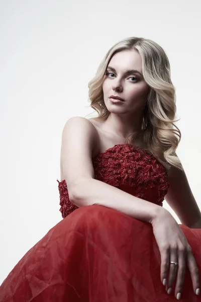 Young blonde in red dress looking at camera in studio — Stock Photo, Image