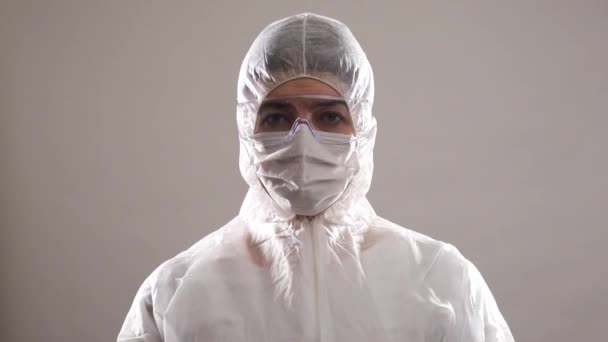 Портрет людини в захисній медичній формі, окулярах та масці для обличчя, що показує знак зупинки — стокове відео
