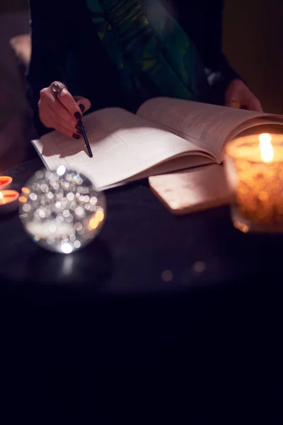 Falcı ellerinin yakın çekimi, tahminler kitapları, tahmin topları siyah masanın üzerinde. — Stok fotoğraf