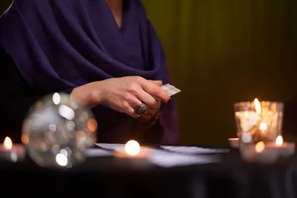 Štěstěna žena ve fialových šatech bohyně na kartách sedí u stolu se svíčkami — Stock fotografie