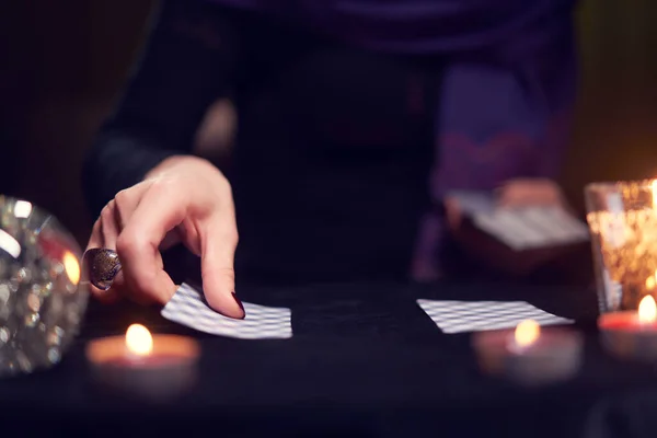 Κοντινό πλάνο των μάντισσων χέρια με κάρτες μαντείας στο τραπέζι με κεριά — Φωτογραφία Αρχείου
