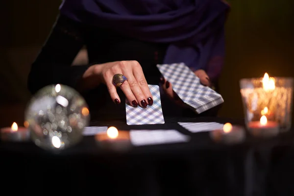 Close-up of female fortunetellers hands with cards at table with candles, magic ball in dark room — Stock Photo, Image
