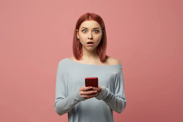 Serieuze gember meisje met telefoon in haar handen staan in de studio — Stockfoto