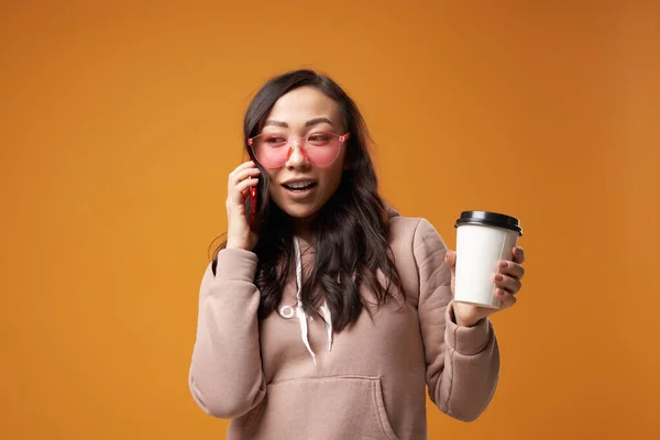 Oriental κορίτσι σε ροζ γυαλιά με γυαλί και τηλέφωνο στα χέρια της στο στούντιο — Φωτογραφία Αρχείου