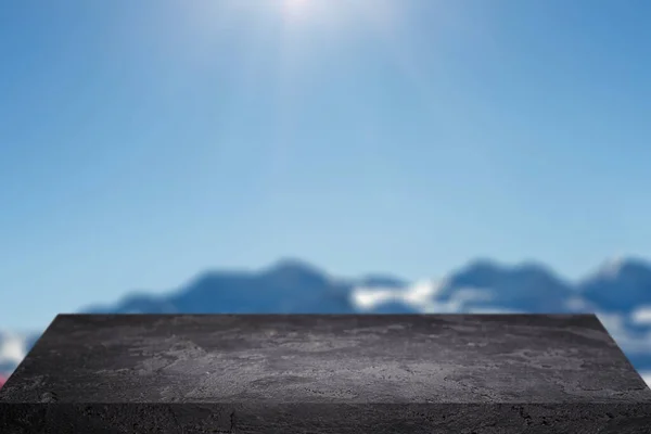 Czarny kamień powierzchni przed błękitnym niebem ze wzgórzami w ciągu dnia. — Zdjęcie stockowe