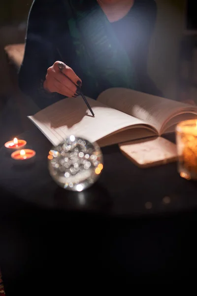 Woman fortuneteller hands, predictions books, predictions ball on black table — Stock Photo, Image